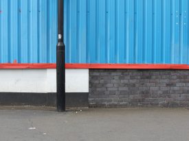 Composition in blue, red, black, white with lampost, bricks, pavement and chewing gum.