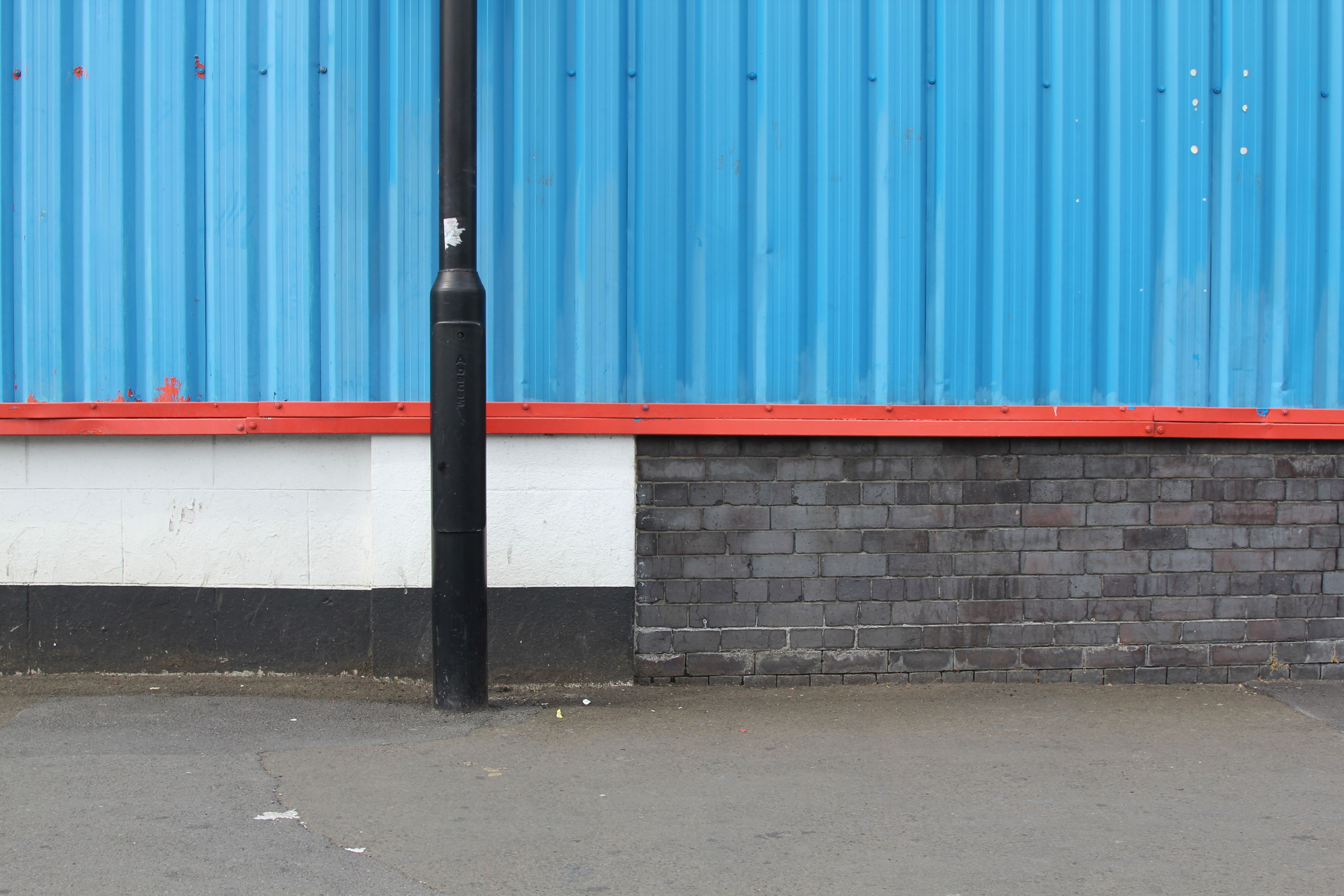 Composition in blue, red, black, white with lampost, bricks, pavement and chewing gum.